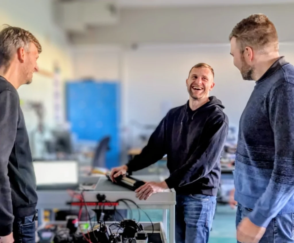 Drei Personen schauen sich eine E-Bike Akku Reparatur an